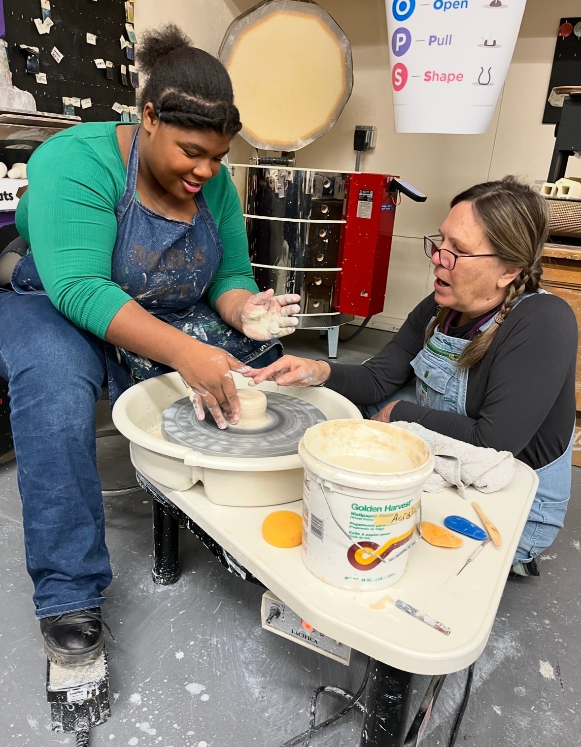 Student learning pottery on a wheel with instructor at The Art Center Alturas