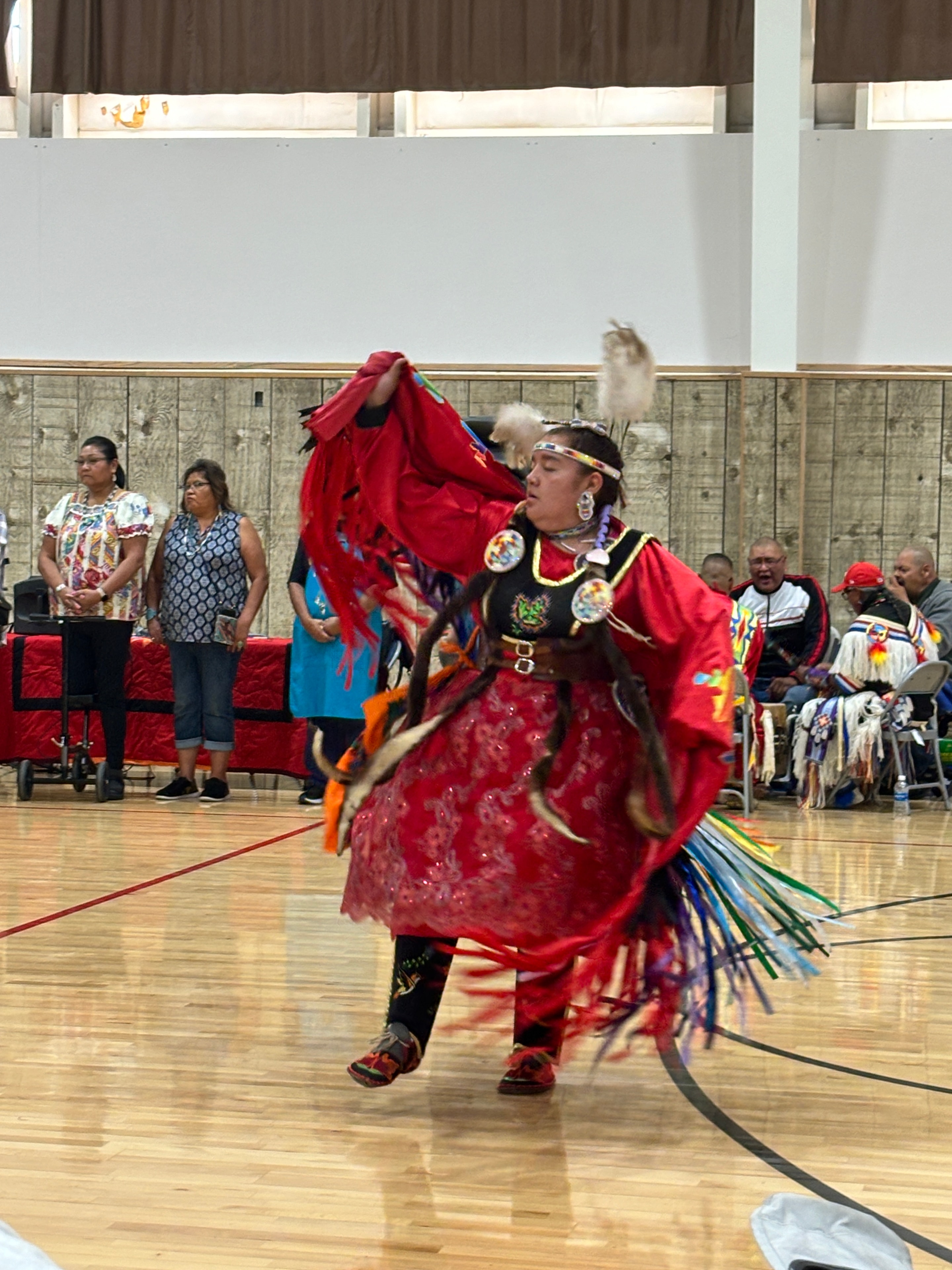 Dancer in traditional red regalia performing at a Sacred Mountain Powwow event